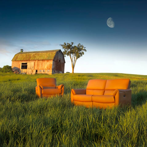 photo d’une causeuse et d’un fauteuil Elran à la ferme, dans un champ avec une grange et un arbre à l’arrière